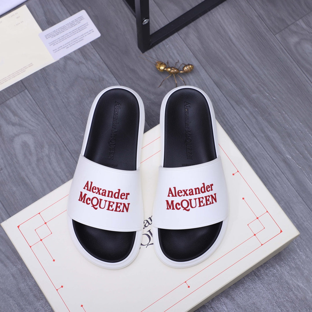 White slide sandals with black footbed and Alexander McQueen logo strap.