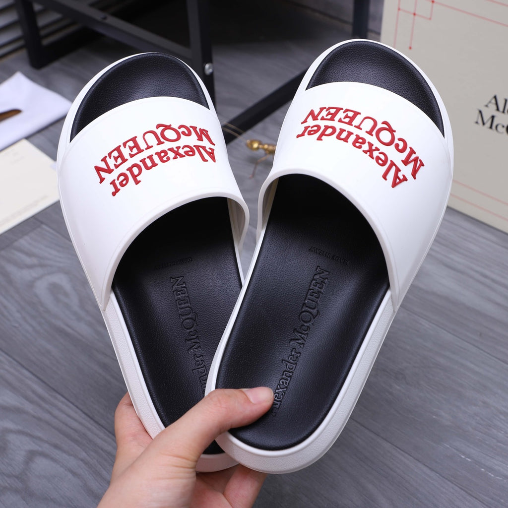White slide sandals with red Alexander McQueen logo on strap and black footbed.