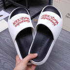 White slide sandals with red Alexander McQueen logo on strap and black footbed.
