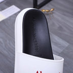 Black footbed with embossed Alexander McQueen text inside a white slide sandal.