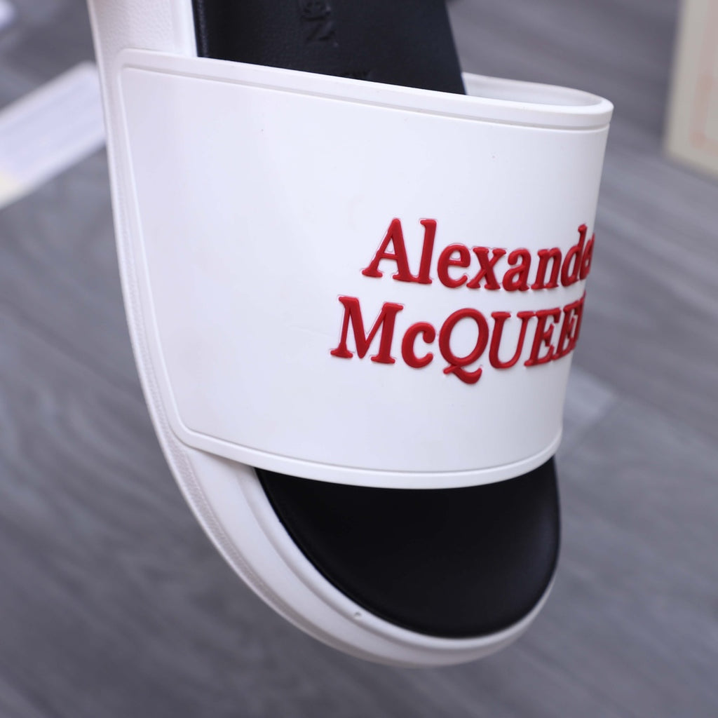 White slide sandal with red Alexander McQueen logo on wide strap and black footbed.