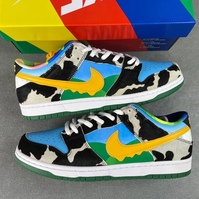 Pair of SB Dunk Low sneakers with black cow print, blue panels, and green accents