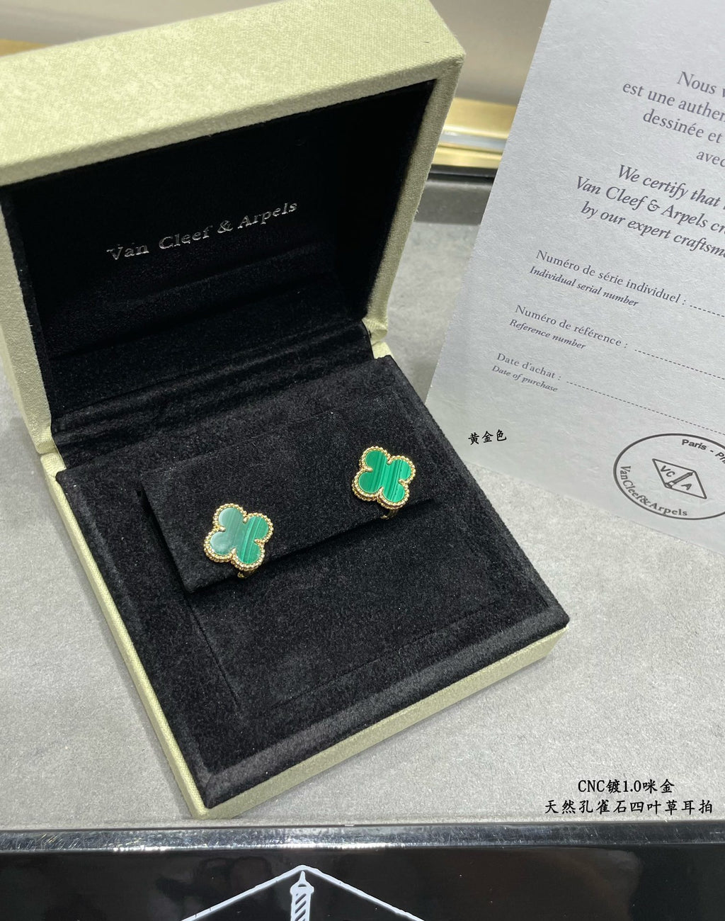 Green enamel four-leaf clover stud earrings in an open black gift box.