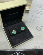 Green enamel four-leaf clover stud earrings in an open black gift box.
