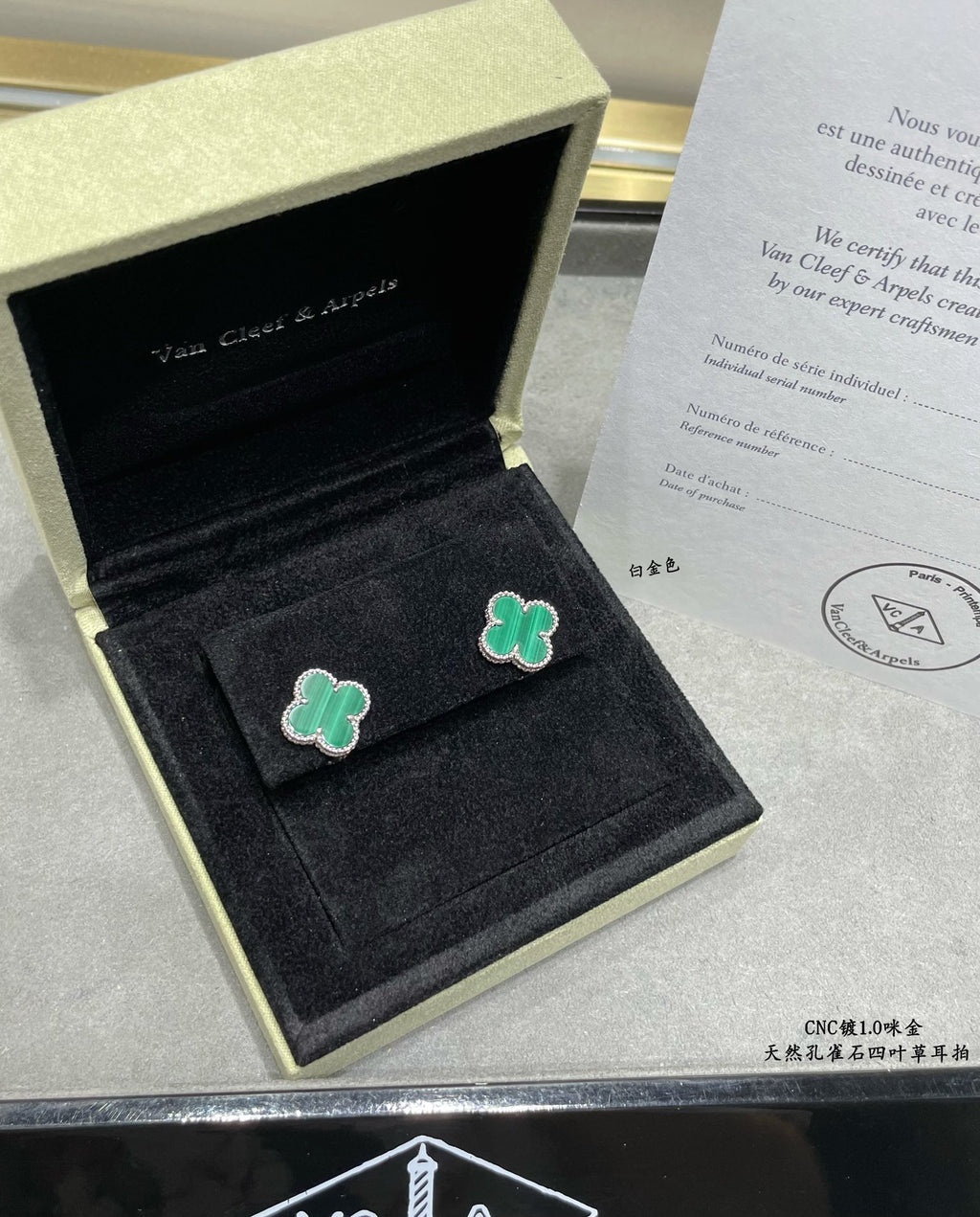 Green enamel four-leaf clover stud earrings resting in an open black box.