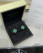 Green enamel four-leaf clover stud earrings on black display cushion.