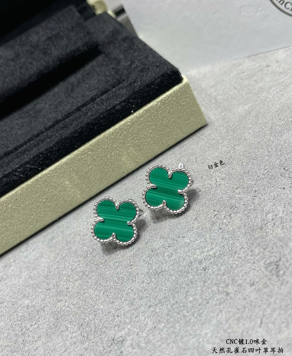 Green enamel four-leaf clover stud earrings with gold-tone outlines on surface.