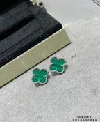 Green enamel four-leaf clover stud earrings with gold-tone outlines on surface.