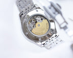 Rolex watch open caseback view with visible movement, silver metal bracelet