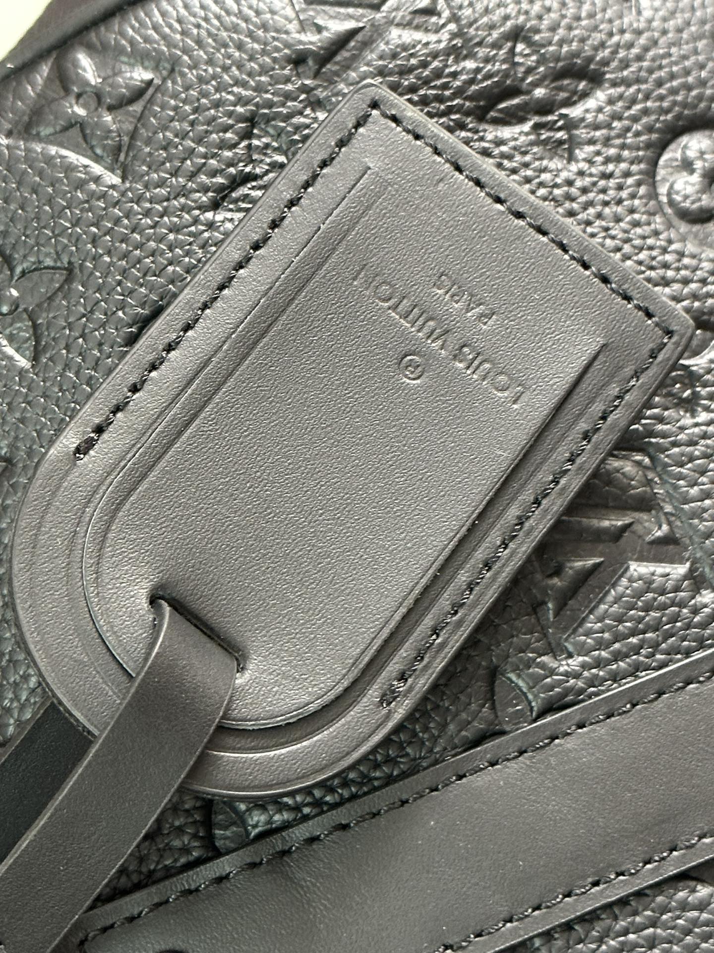 Men's Louis Vuitton leather luggage tag detail on monogram bag