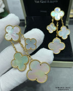 Gold-tone clover dangle earrings with mother-of-pearl charms on white glove