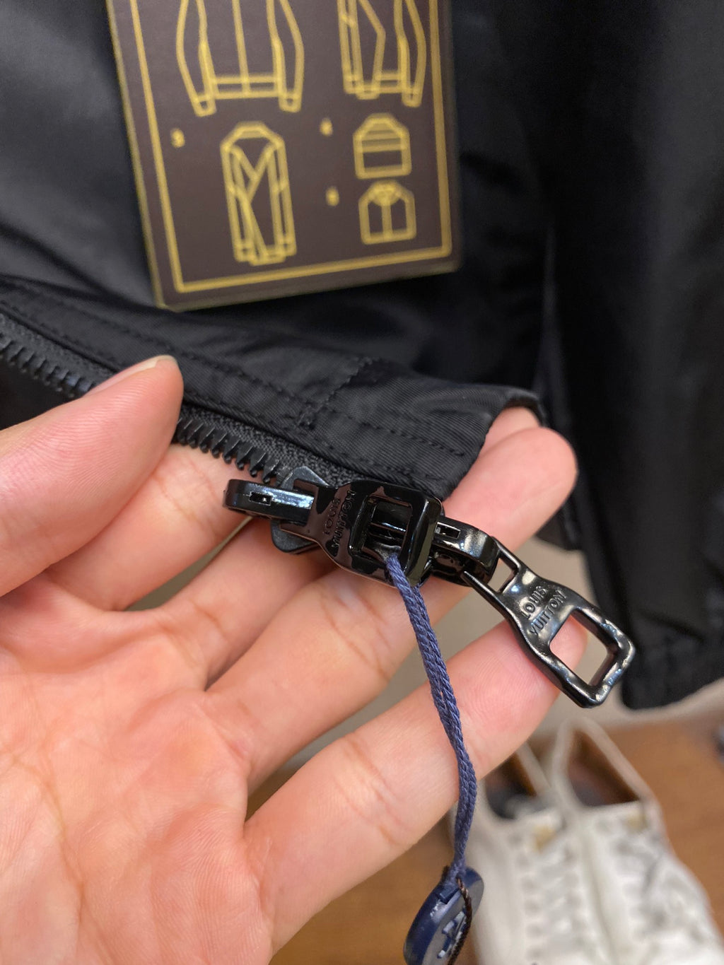 Black jacket zipper pull with blue drawstring and metal toggle