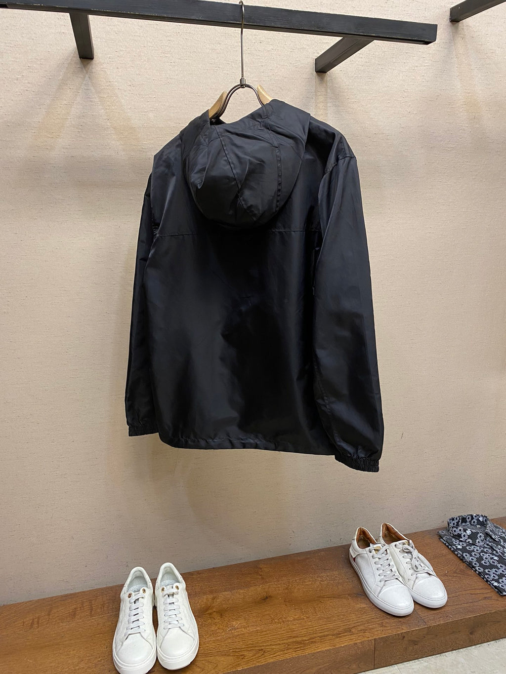 Black hooded jacket, back view with full-zip front and drawstring hem