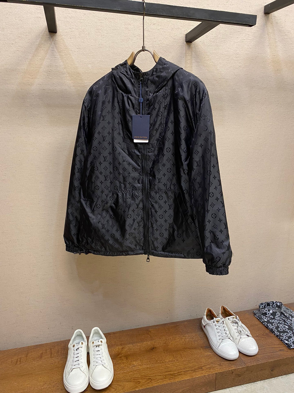 Black hooded jacket with subtle monogram pattern, front zipper and drawstring hem
