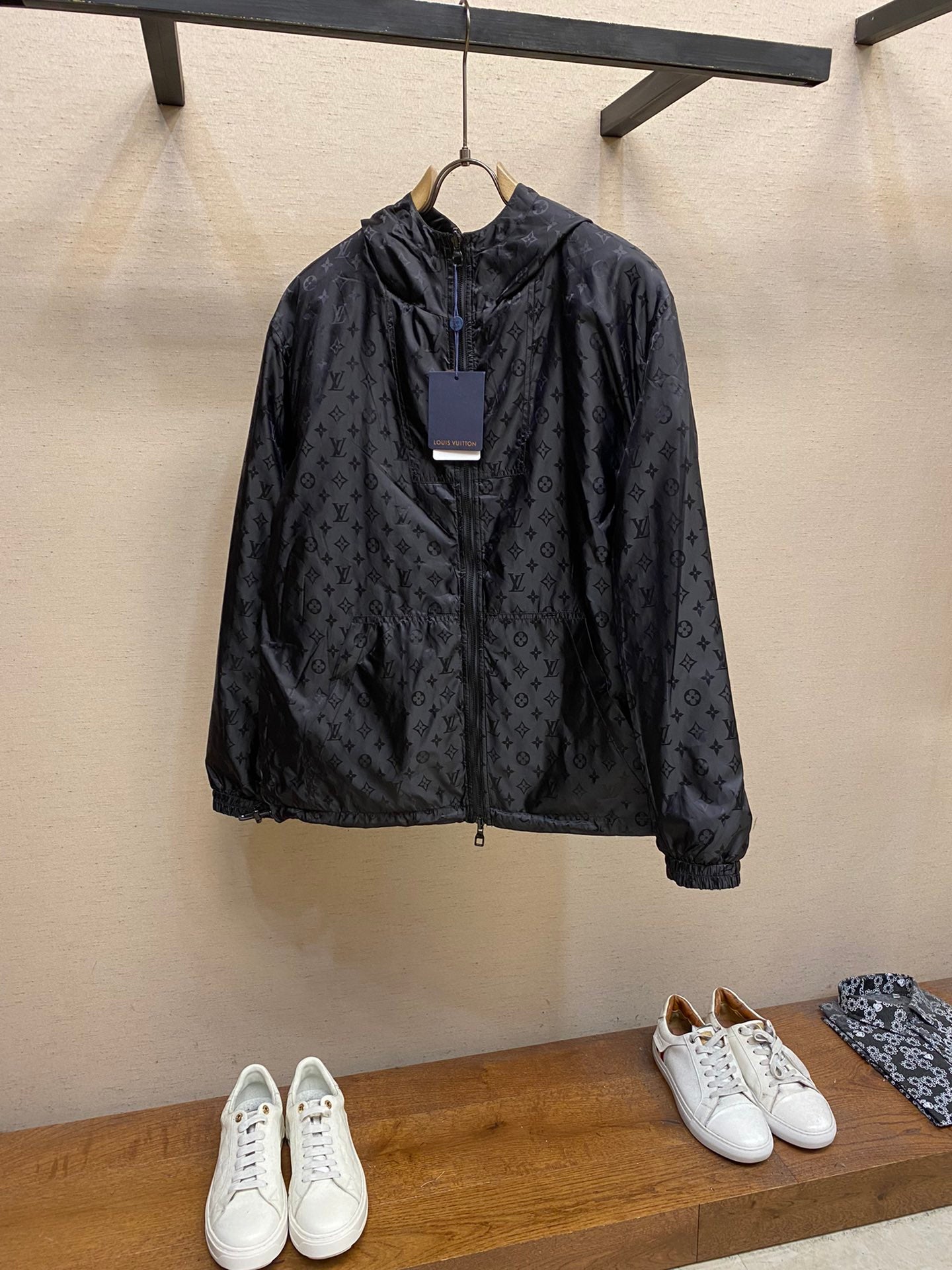 Black hooded jacket with subtle monogram pattern, front zipper and drawstring hem