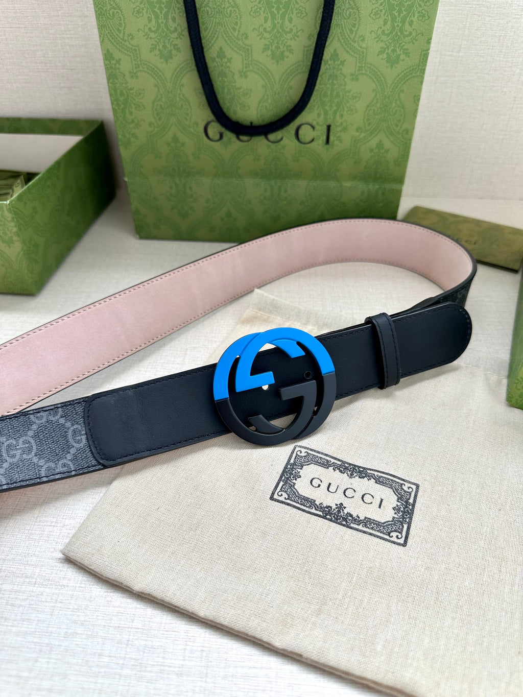 Designer belt with dark navy strap and blue interlocking buckle, laid flat