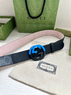 Designer belt with dark navy strap and blue interlocking buckle, laid flat