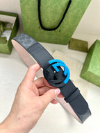 Designer belt with dark blue strap, monogram panel, and blue interlocking buckle