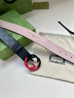 Designer belt with light pink underside and red interlocking buckle, angled view
