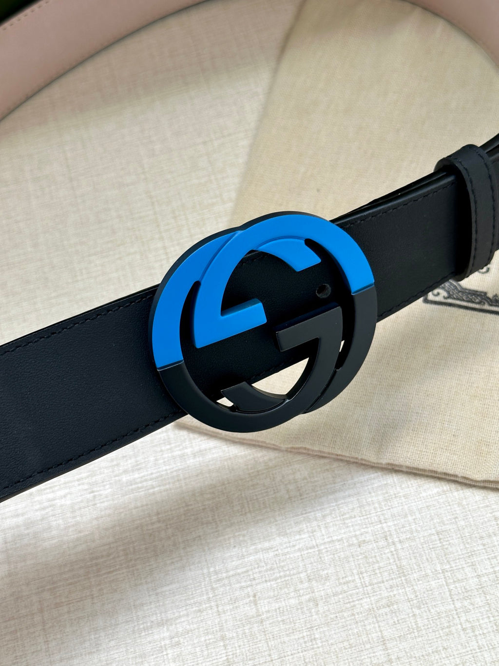 Gucci belt buckle close-up with navy strap and blue circular G logo