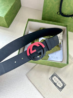 Designer belt with dark blue strap and pink/red GG buckle, flat laid view
