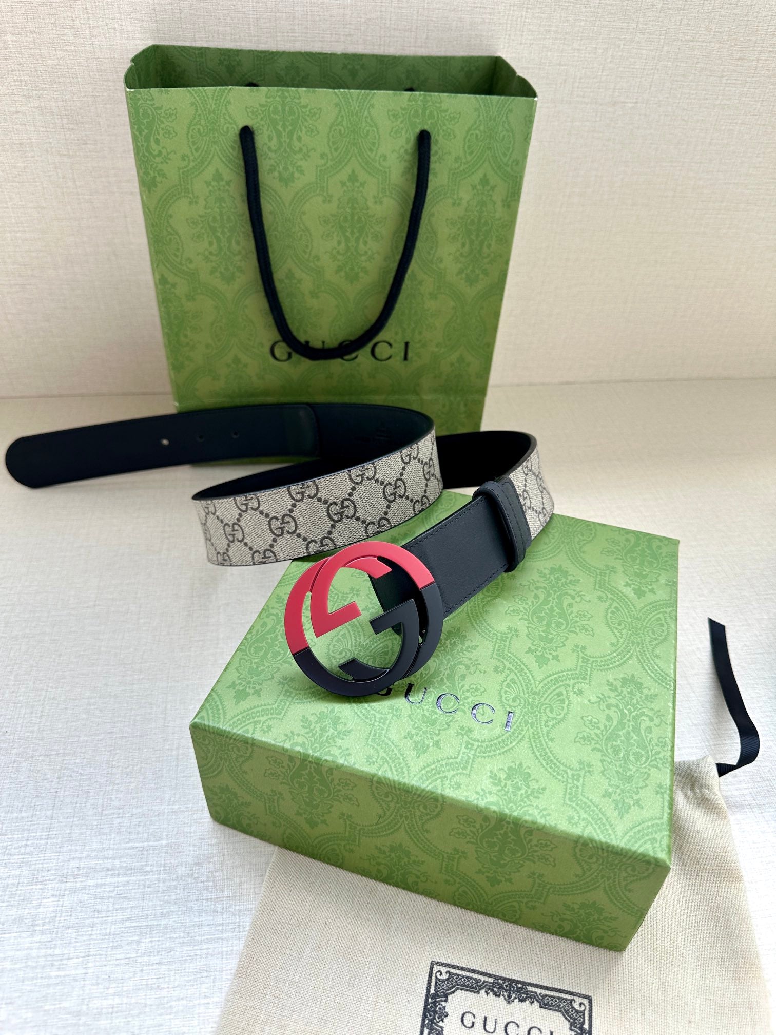 Designer belt with gray GG canvas, dark blue edges, and pink/red GG buckle