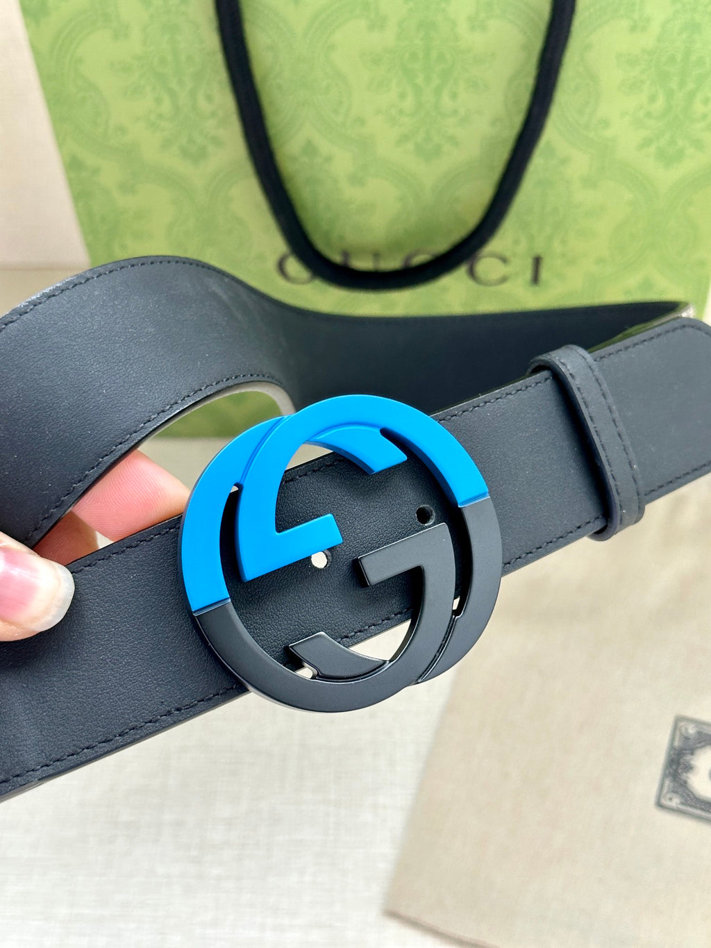 Dark blue leather belt with close-up of round GG buckle and blue outer ring