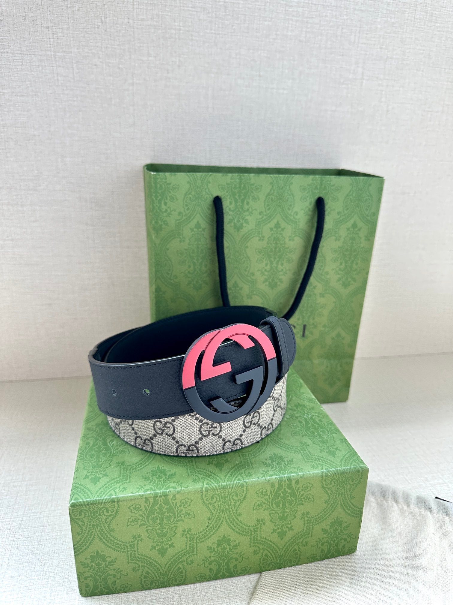 Dark blue leather belt with gray GG canvas strap and pink/red GG buckle