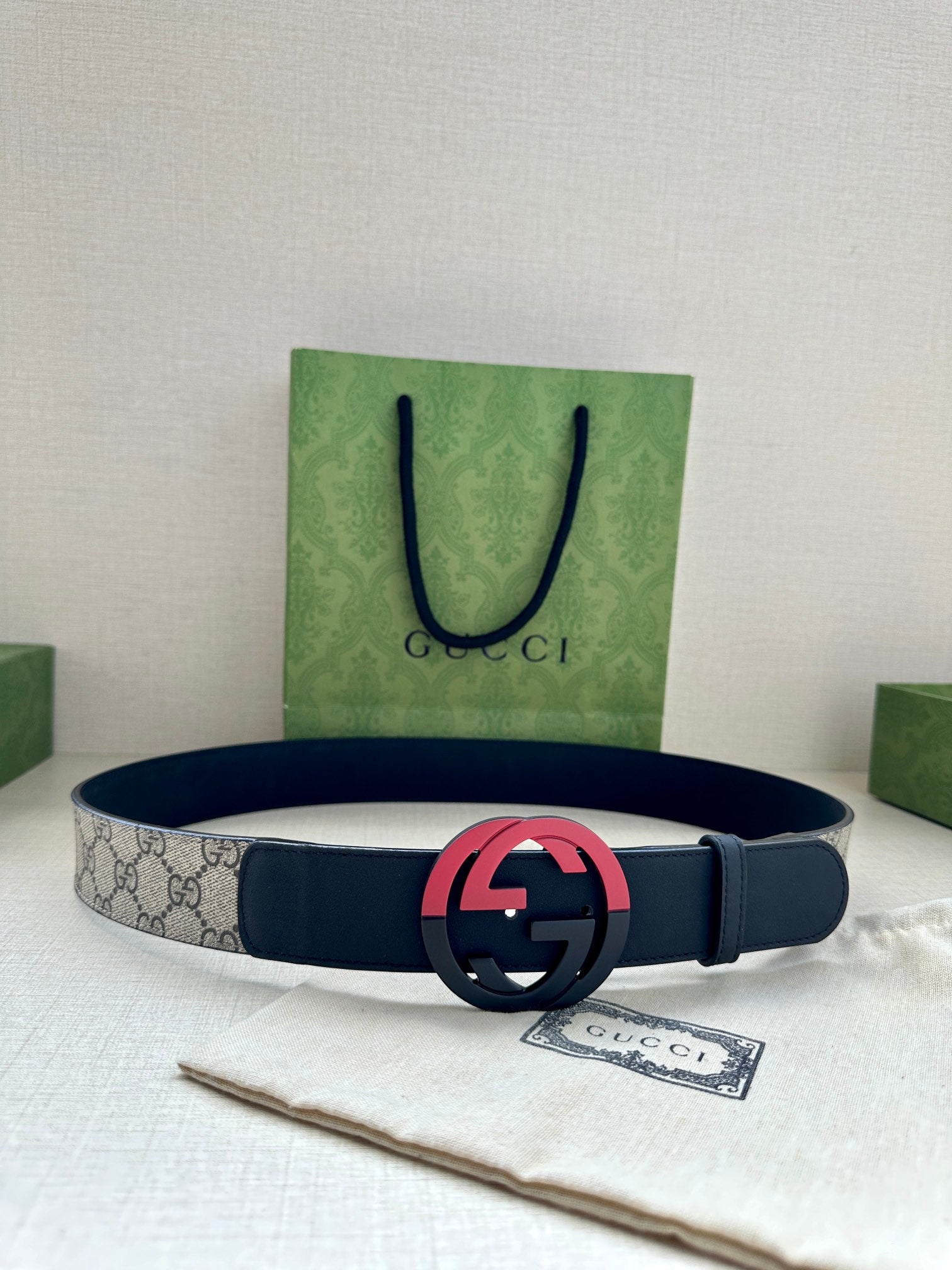 Dark blue leather belt with gray canvas center and pink/red GG buckle