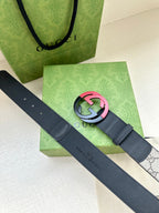 Designer belt with dark blue leather and pink/accent round GG buckle over gray strap