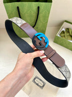 Brown and beige GG-print belt with round black buckle and dark underside, handheld