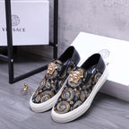 Versace slip-on sneaker pair, dark upper with gold and blue baroque pattern, white rubber sole