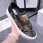 Versace slip-on sneaker on hand, dark fabric upper with gold and blue medallion print, white sole
