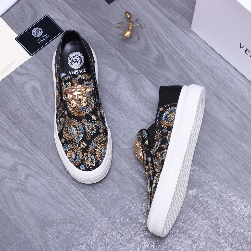 Versace slip-on sneaker angle view, dark patterned upper with gold ornament, white sidewall sole