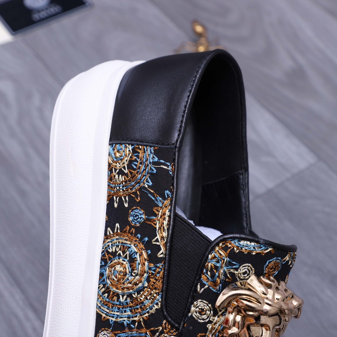 Versace slip-on sneaker close-up, dark upper with gold ornament and blue pattern, white sole