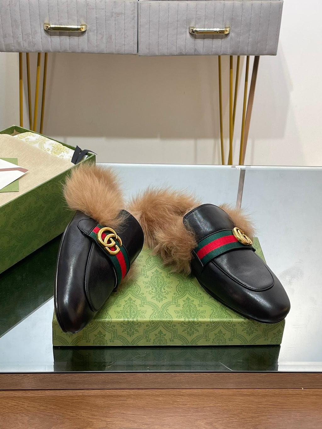 Gucci black fur slide sandals on green box: green-red web strap, gold GG buckle