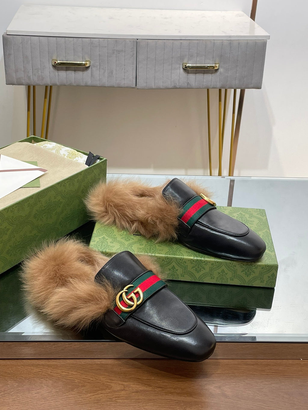 Gucci black fur slides with green-red web strap and gold GG buckle, pair on box