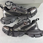 Two black and silver Balenciaga sneakers with black laces and thick tread sole on box