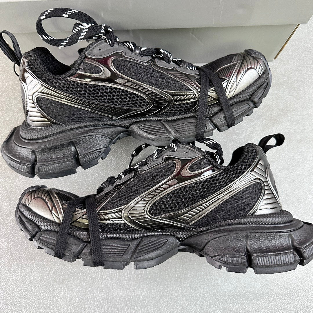 Two black and silver Balenciaga sneakers with black laces and thick tread sole on box
