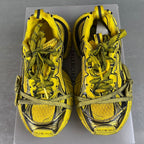 Balenciaga sneakers front view, yellow uppers with black graphic overlays and green laces