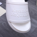 White slide sandal close-up: embossed logo on upper band
