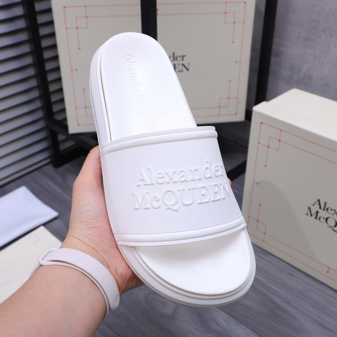 White slide sandal with wide band strap and embossed logo detail on upper
