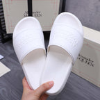 White slide sandals with embossed logo on footbed, shown from side angle