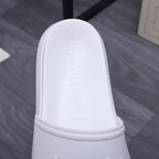 White slide sandal close-up: textured footbed with embossed brand name