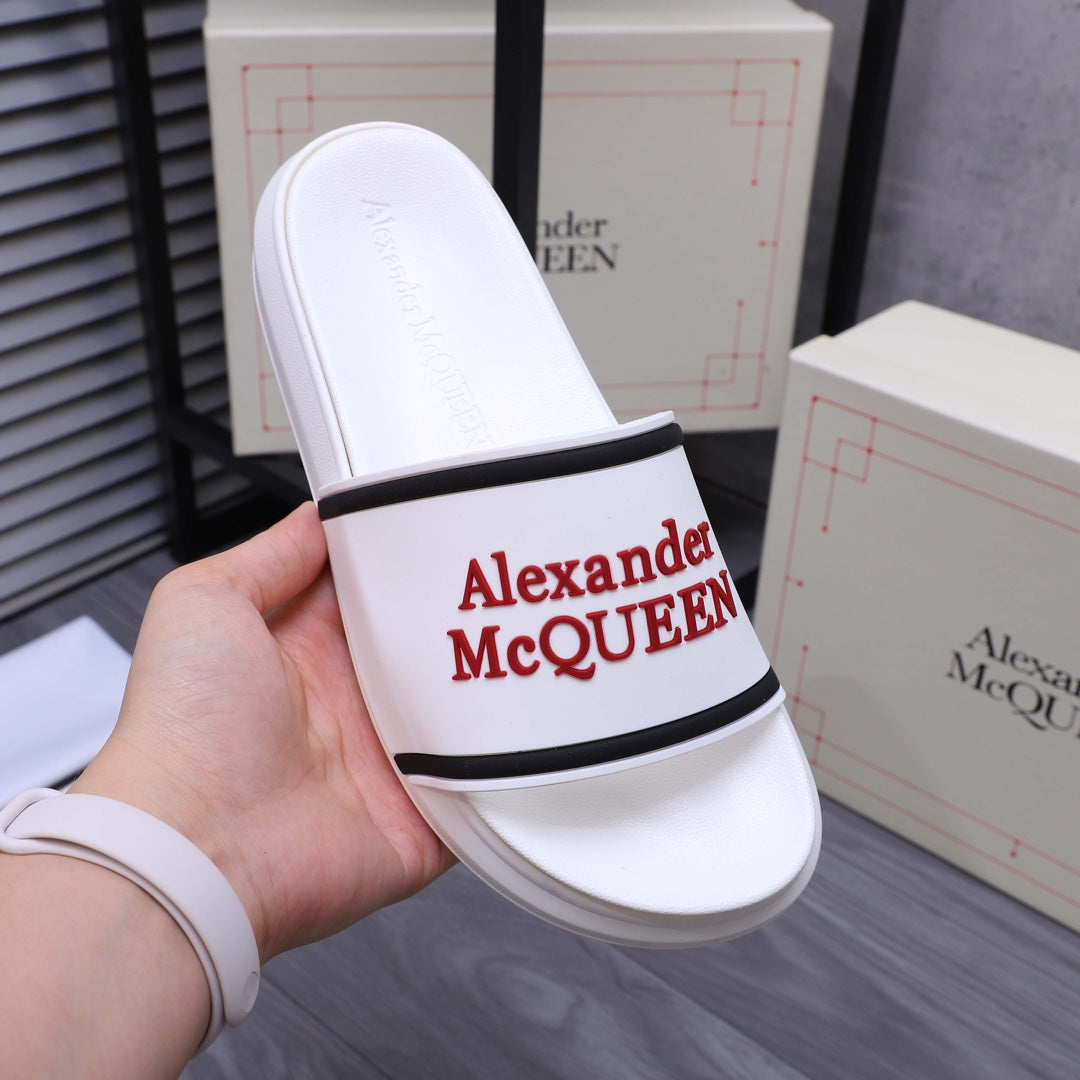 White slide sandal with black trim band and red Alexander McQUEEN on strap