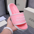 Pink slide sandal shown from side with wide strap and Alexander McQueen logo