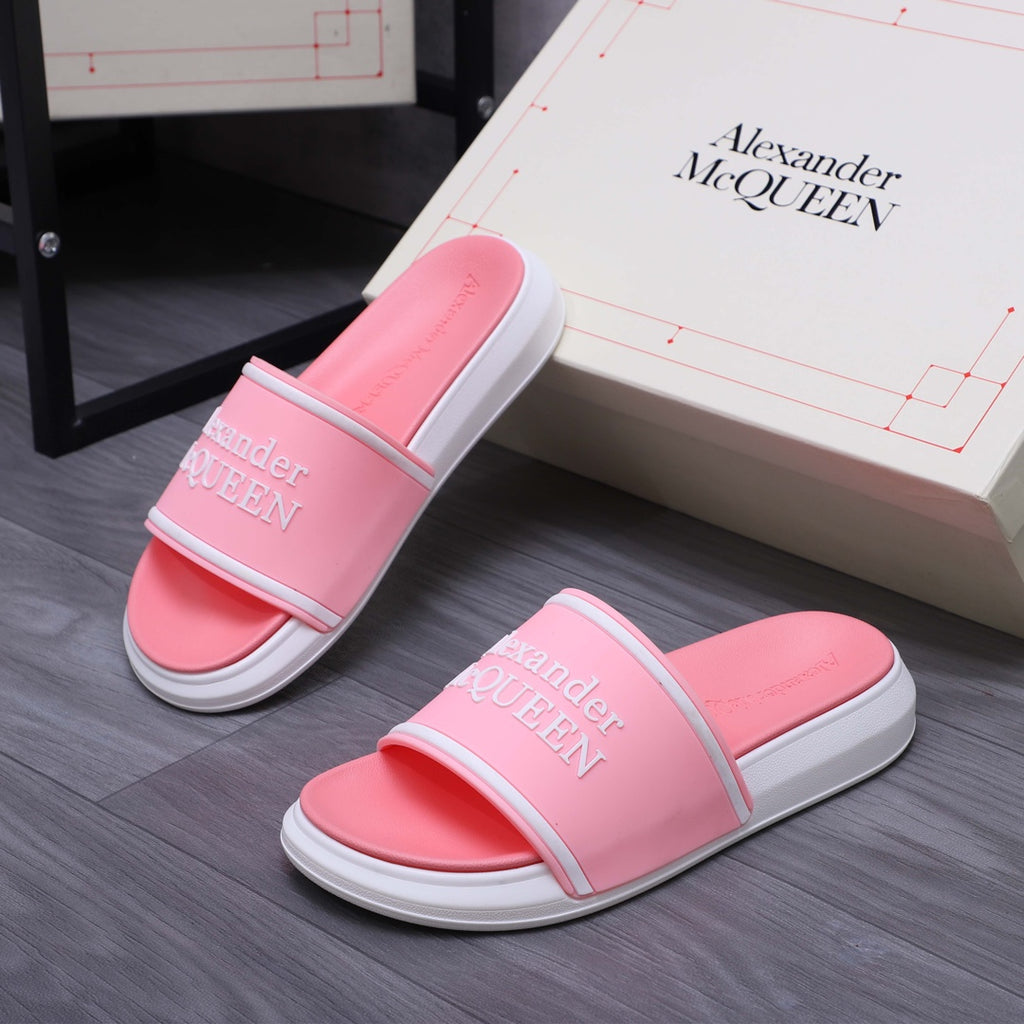 Pink slide sandals with wide strap and Alexander McQueen logo, pair on floor