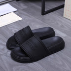 Alexander McQueen black slide sandals, logo-embossed strap, side view of pair