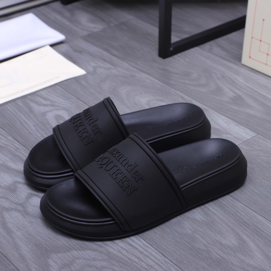 Alexander McQueen black slide sandals, logo-embossed strap, side view of pair