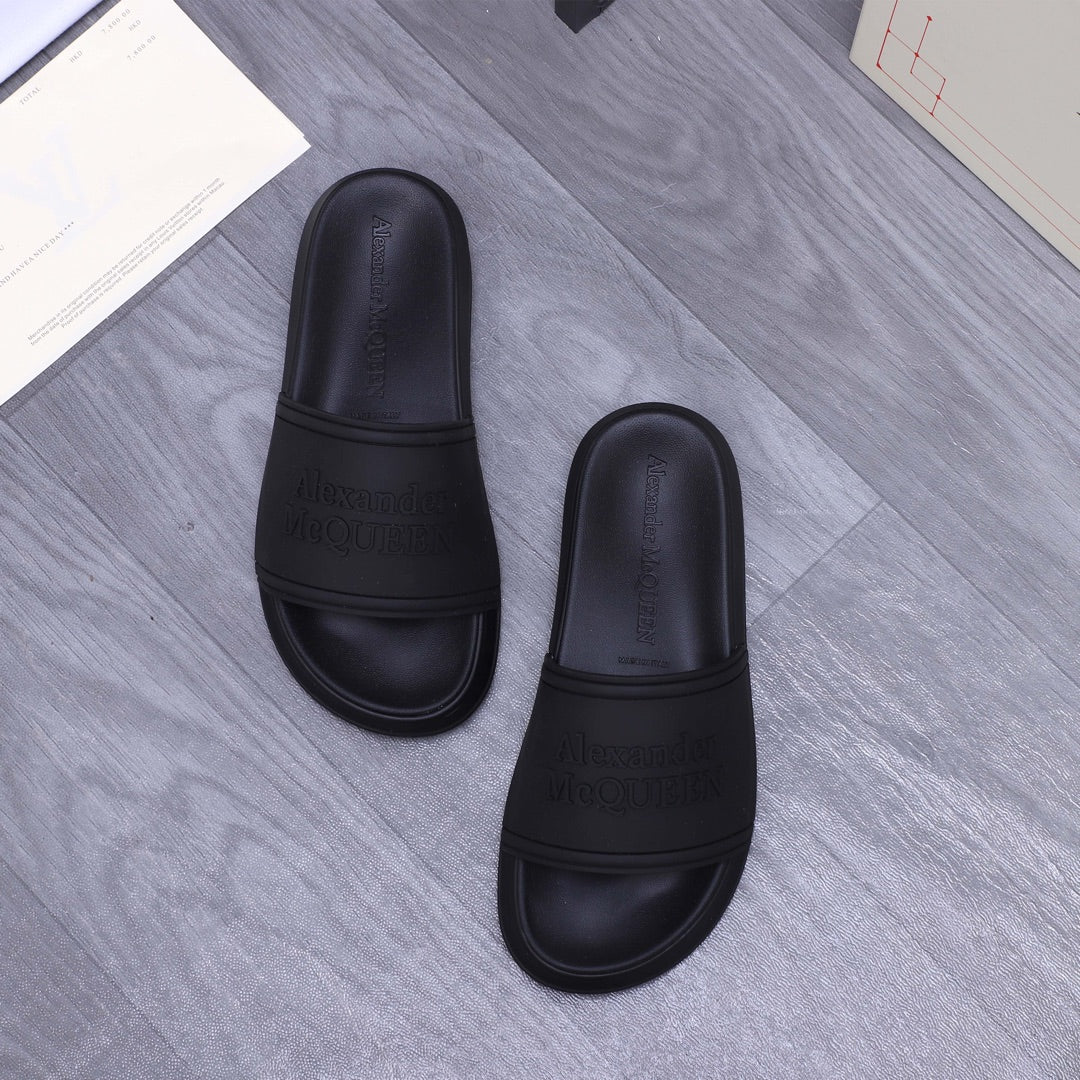 Alexander McQueen black slide sandals, two shoes shown with embossed logo details